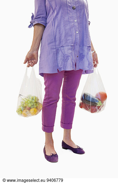 Senior woman holding fruits and vegetables in plastic bag