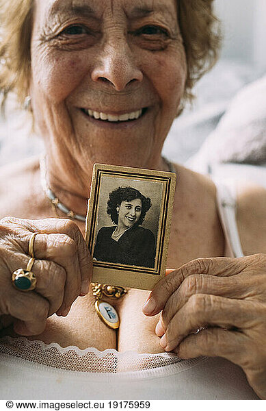 Senior woman holding old picture at home