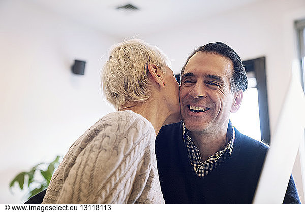 Senior woman kissing husband at home