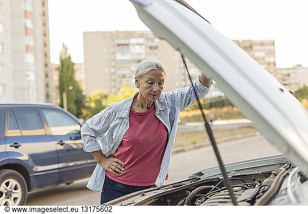 Senior woman looking at car engine