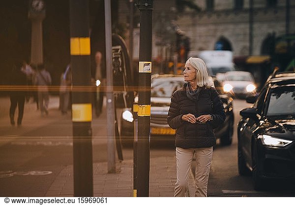 Senior woman looking away while walking in city