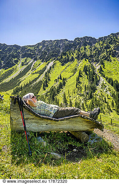 Senior woman lying on wooden bench  Mountain Nebelhorn  Allgau  Bavaria  Germany