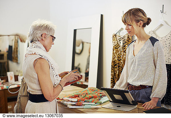 Senior woman paying after shopping in boutique store