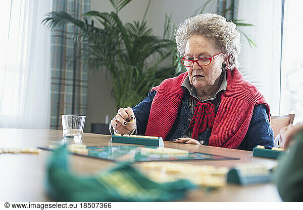 Senior woman playing board game in rest home
