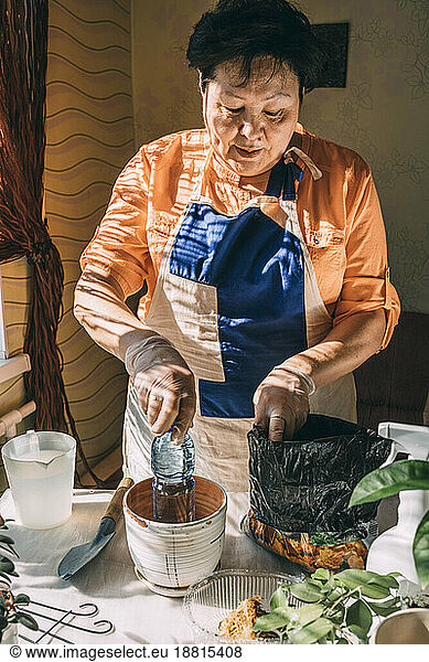 Senior woman preparing for planting on table at home
