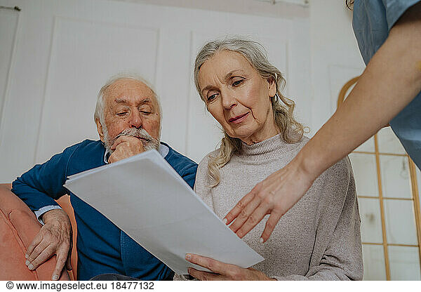 Senior woman reading medical report with man at home