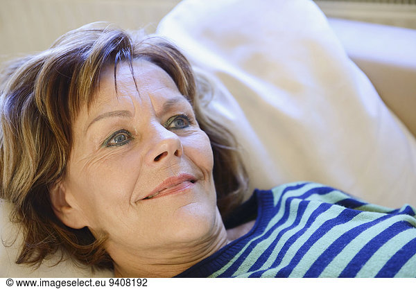 Senior woman relaxing and daydreaming on couch  smiling