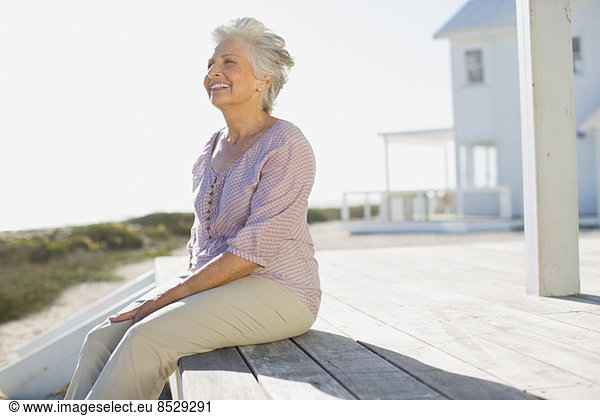Senior woman sitting on deck outside beach house