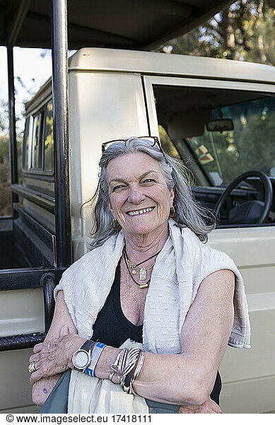 Senior woman smiling standing by a safari jeep in Botswana.