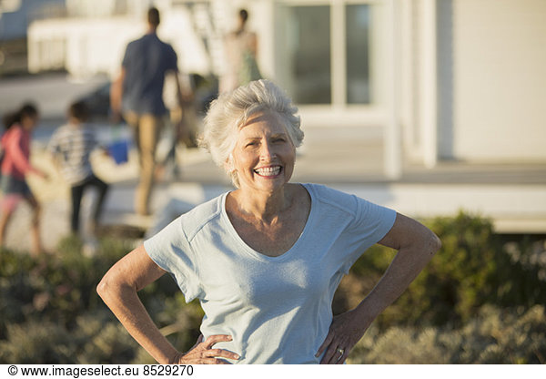 Senior woman smiling with hands on hips outdoors
