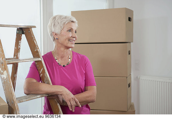 Senior woman standing with step ladder in new apartment