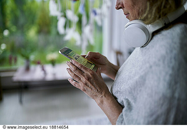 Senior woman text messaging and using smart phone at home