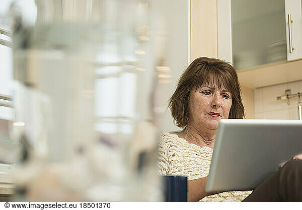 Senior woman using a digital tablet in the kitchen  Munich  Bavaria  Germany