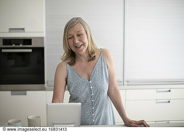 Senior woman using digital tablet in kitchen