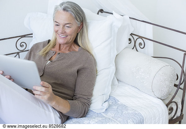 Senior woman using digital tablet on bed