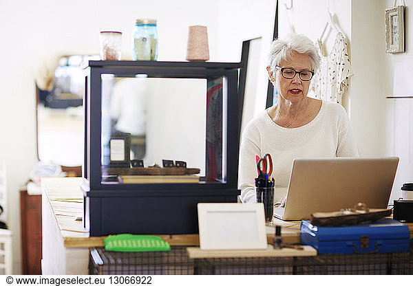 Senior woman using laptop computer in boutique store