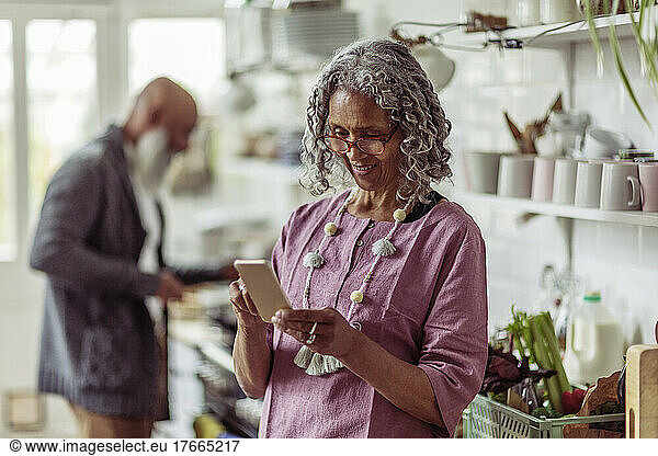 Senior woman using smart phone in kitchen