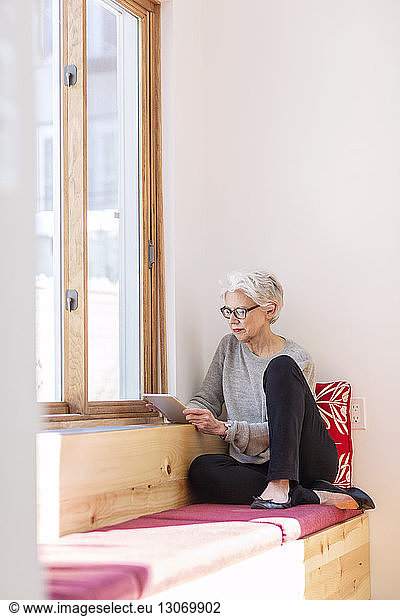 Senior woman using tablet computer while sitting at home