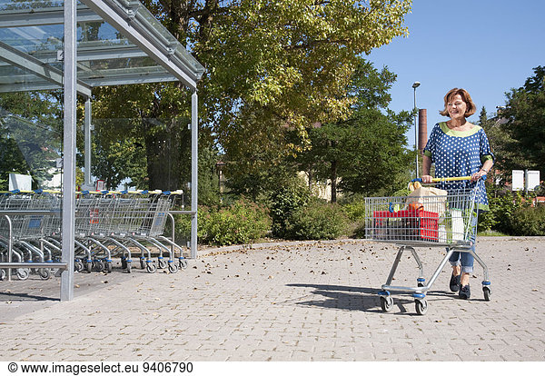 Senior woman walking with shopping cart
