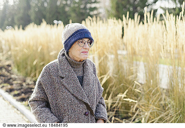 Senior woman wearing warm clothing strolling in park
