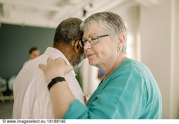 Senior woman with eyes closed dancing with man in class