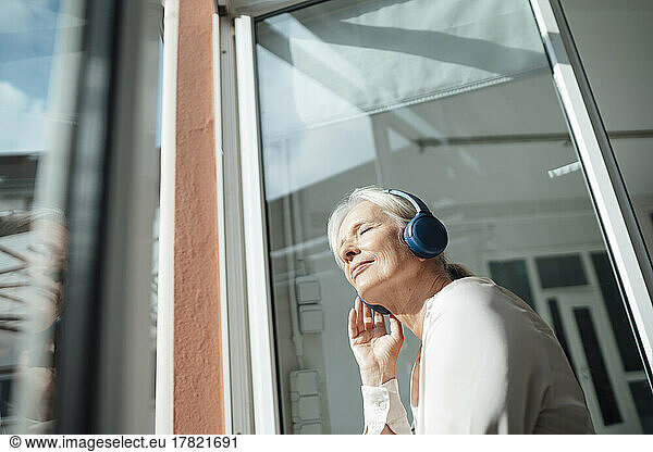 Senior woman with eyes closed listening music through wireless headphones