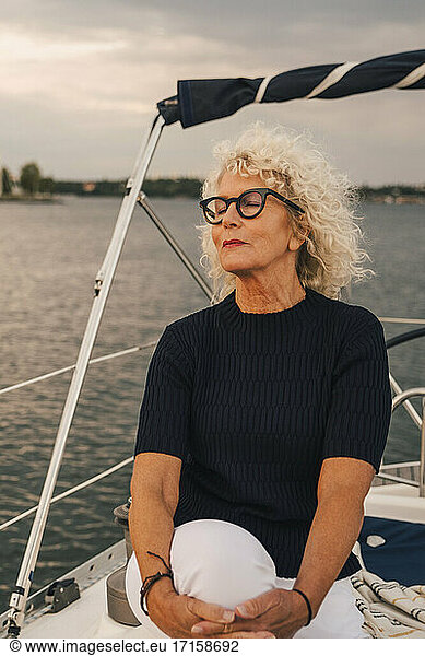 Senior woman with eyes closed sitting on boat during sunset