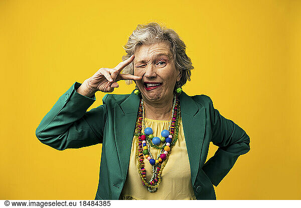 Senior woman with facial expressions against yellow background