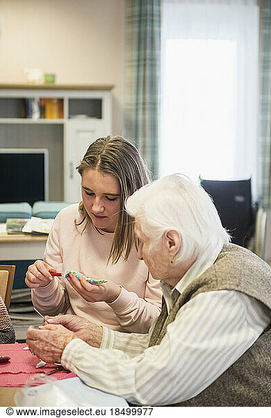 Senior woman with girl making rabbit during Easter at rest home