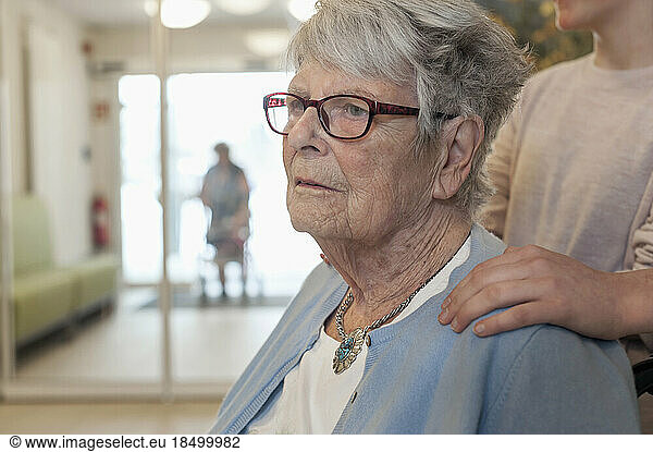 Senior woman with hand on shoulder of grand child in rest home