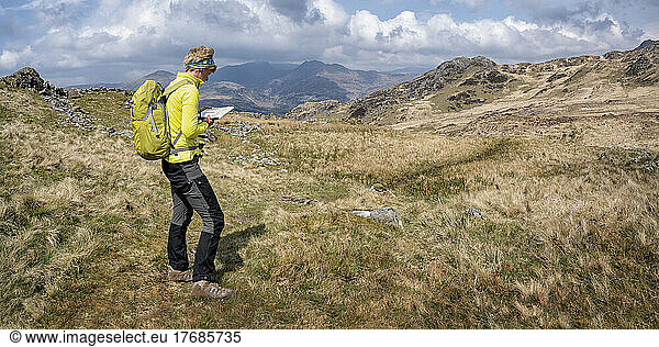 Senior woman with map standing on Y Garn mountain ridge