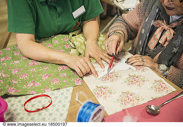 Senior woman with nurse making rabbit shape on fabric during Easter at rest home