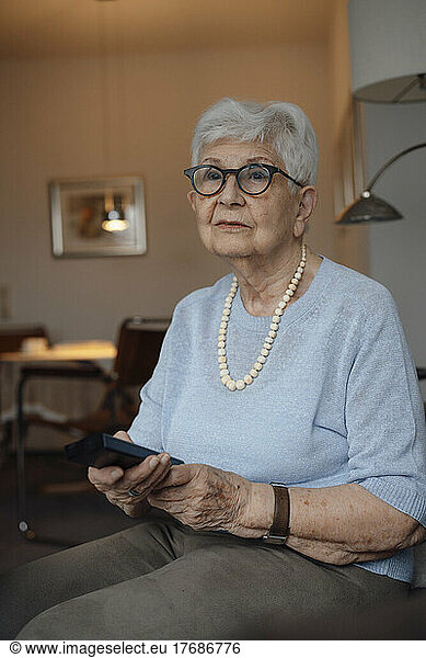 Senior woman with remote control sitting at home