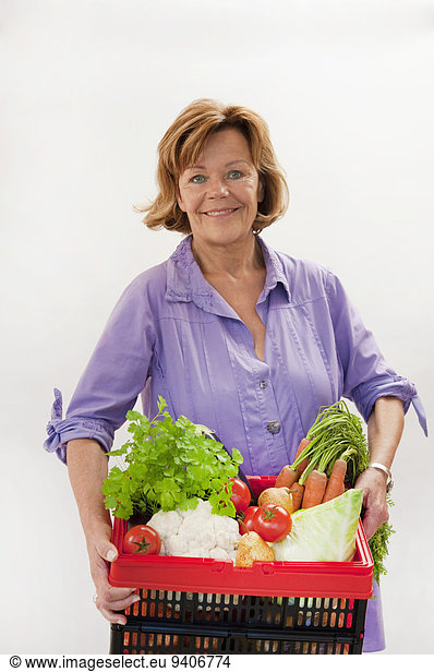 Senior woman with vegetable basket  smiling  portrait