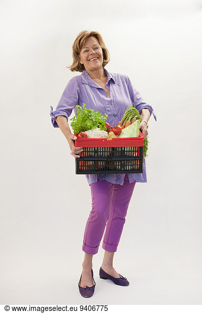 Senior woman with vegetable basket  smiling  portrait