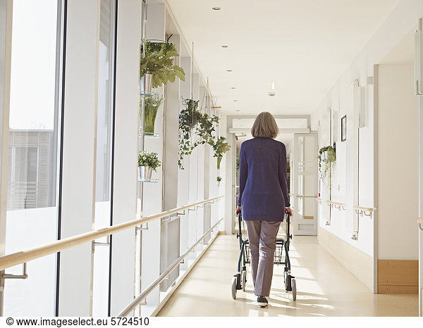 Senior woman with walking frame at corridor in nursing home