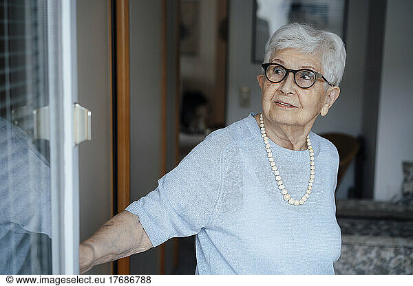 Senior woman with white hair standing at doorway