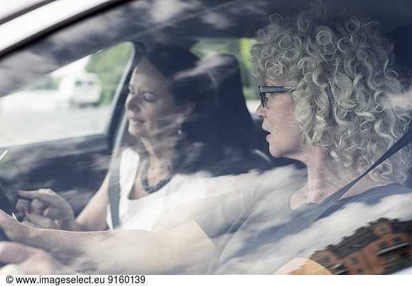 Senior women discussing over digital tablet in car