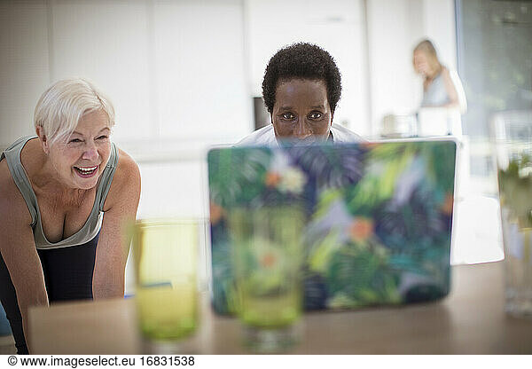 Senior women friends exercising at laptop