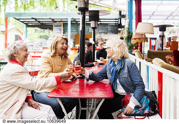Senior women toasting wineglasses while sitting at restaurant