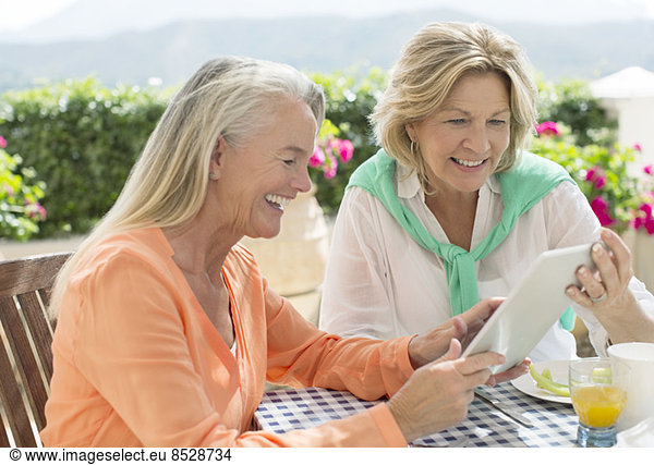 Senior women using digital tablet at patio table