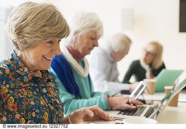 Senior women using laptops in conference room meeting