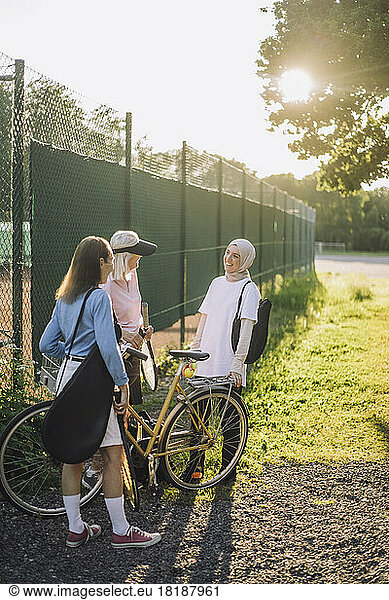 Senior women with bicycle talking to female friend on sunny day