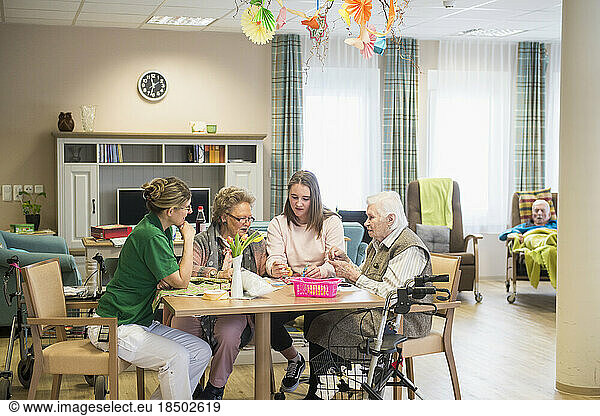 Senior women with girl and nurse doing craft activity at rest home