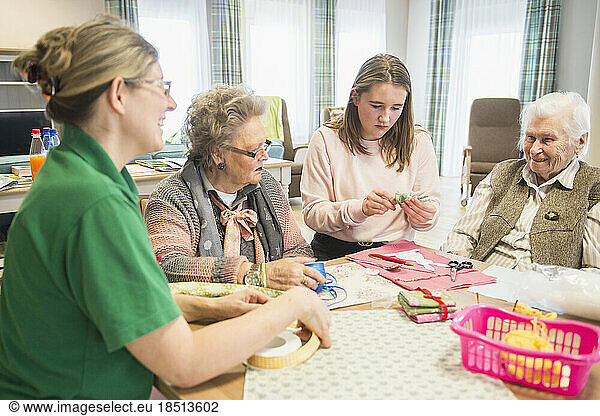 Senior women with girl and nurse doing craft activity at rest home