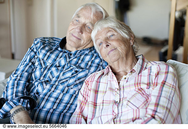 Seniorenpaar entspannt sich gemeinsam auf dem Sofa im Wohnen