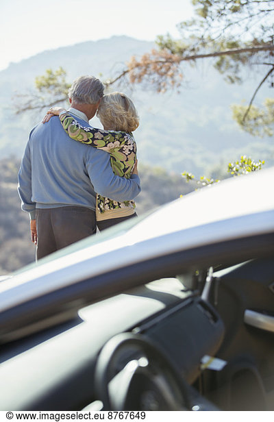 Seniorenpaar mit Blick auf die Berge außerhalb des Autos