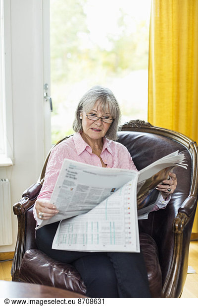 Seniorin beim Zeitungslesen zu Hause