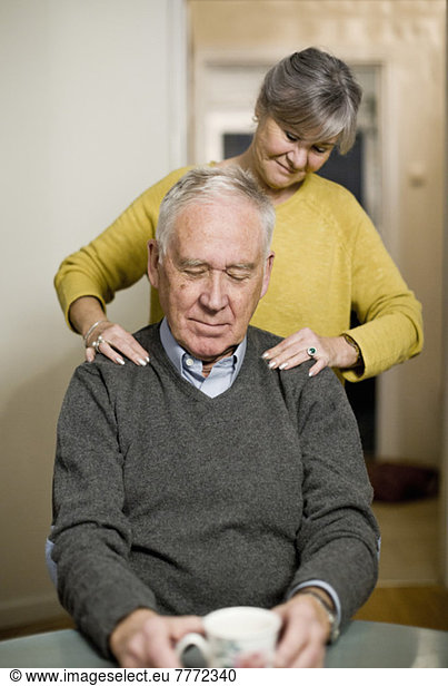 Seniorin gibt dem Mann zu Hause eine Schultermassage