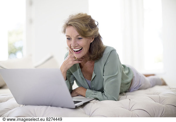 Seniorin mit Laptop im Wohnzimmer